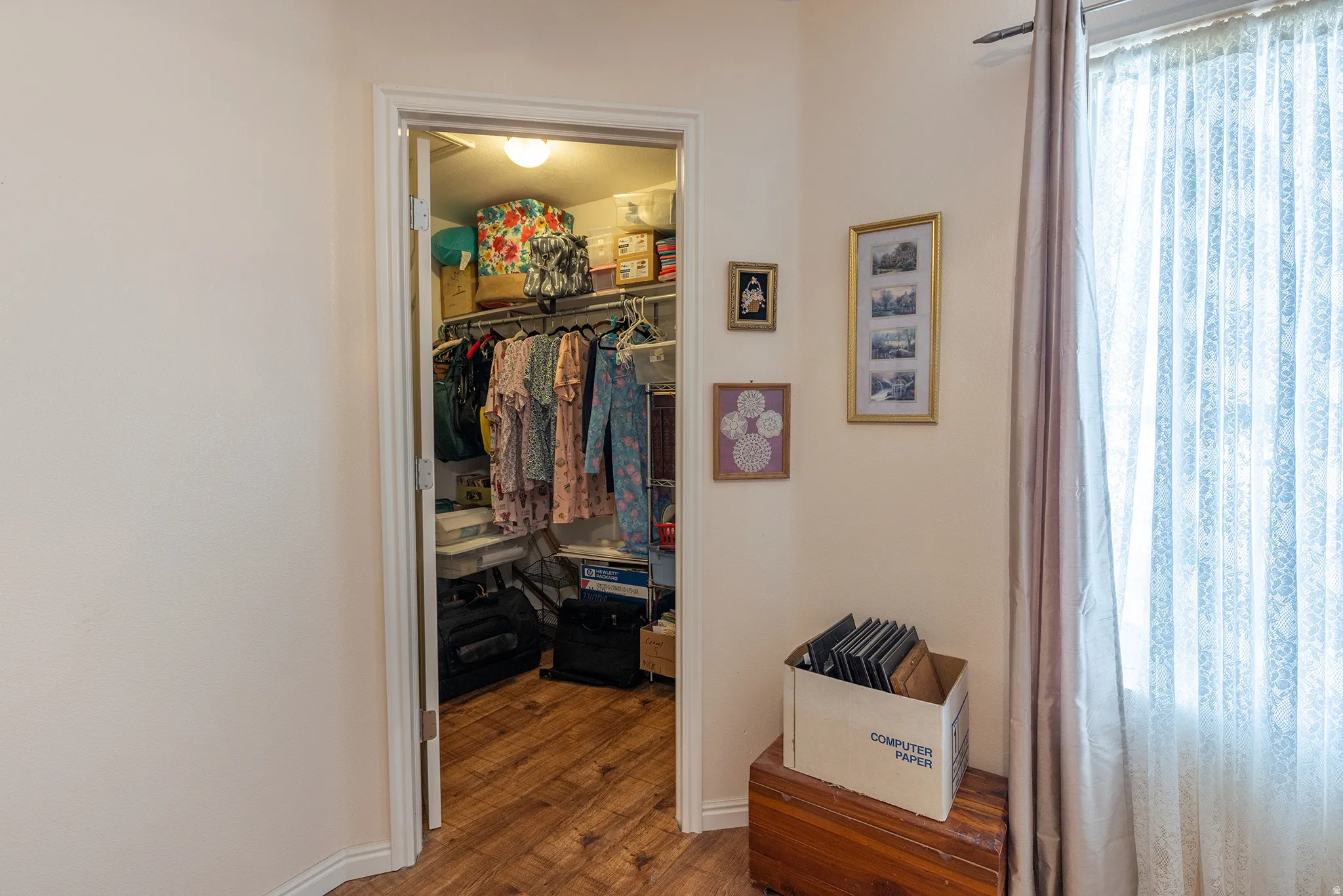 Spacious walk-in closet with wood-finish flooring, built-in clothing rod with multiple hanging sections, and shelving storage