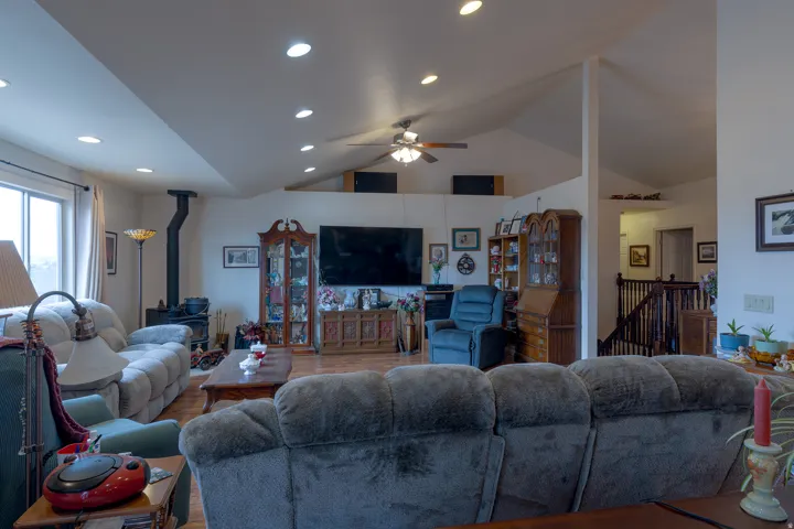 Vaulted ceilings with recessed lighting, wood-finish flooring, and a built-in wood stove