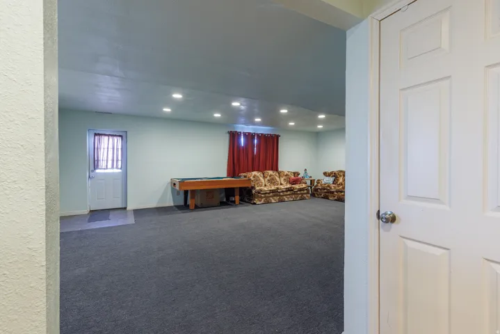 Recessed lighting illuminates the expansive carpeted area with a secondary entrance, offering flexible space