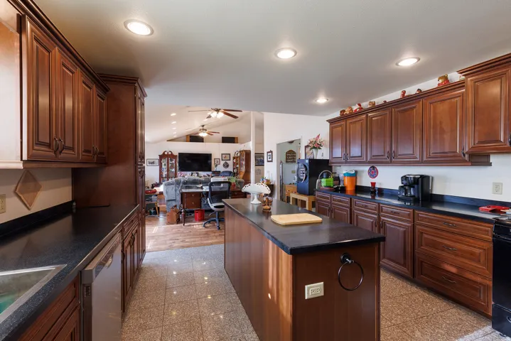Kitchen featuring extensive wood-finish cabinetry, dark countertops, recessed lighting, and a center island