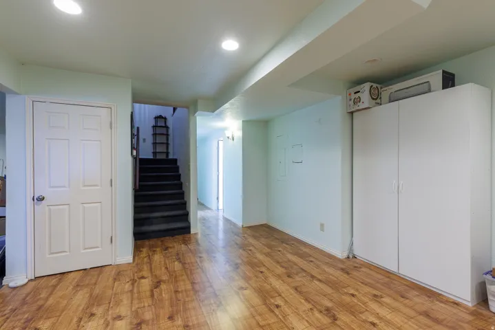Wood-finish flooring with recessed lighting, white paneled doors, and built-in white cabinetry