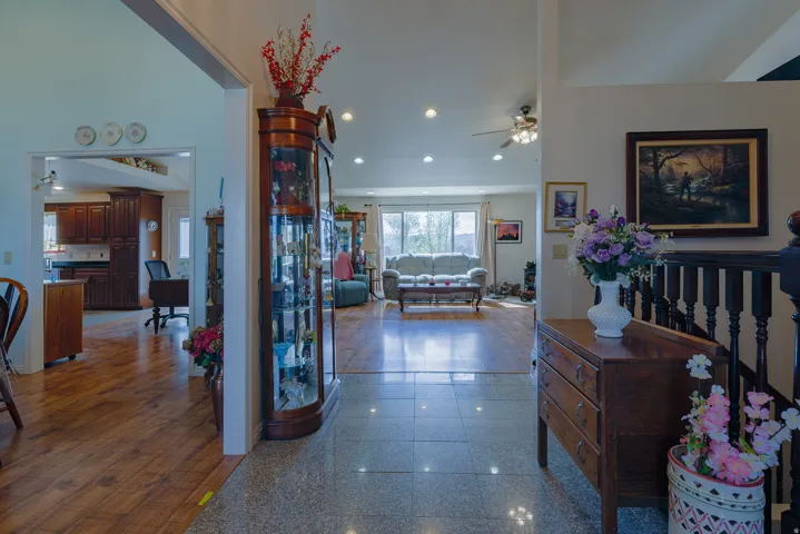 Tiled entryway leading to wood-finish flooring in the living area, featuring recessed lighting and a ceiling fan