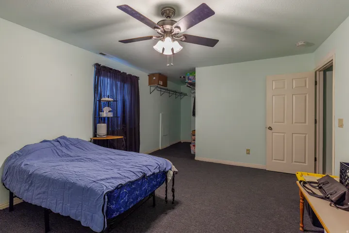 Recessed lighting, ceiling fan with light fixture, light blue wall paint, paneled interior door, and dark carpeting