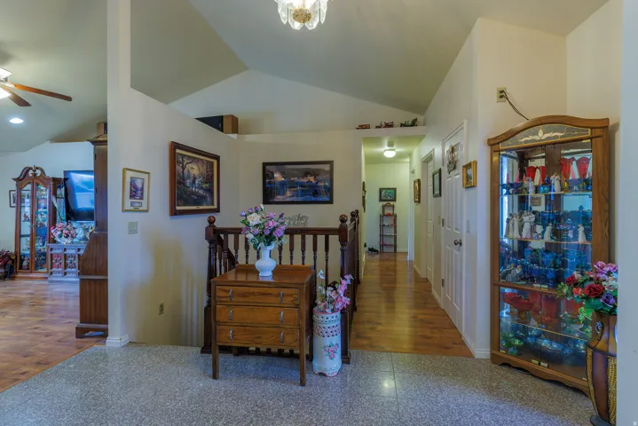 Vaulted ceilings, wood-finish flooring, staircase with wood railing, and a crystal chandelier