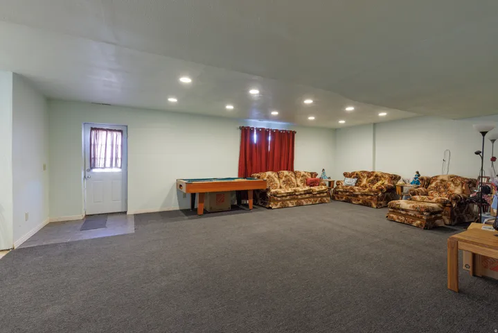Spacious room featuring recessed lighting, light-toned wall paint, and dark gray carpeting