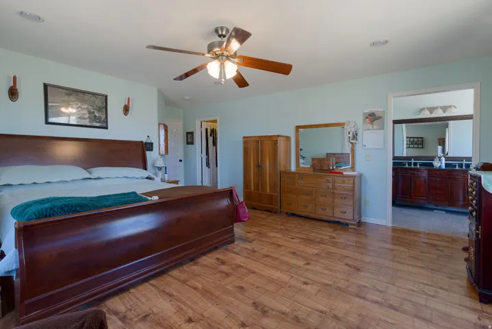 Wood-finish flooring, ceiling fan with integrated lighting, recessed lighting, and a doorway to a bathroom with a double vanity