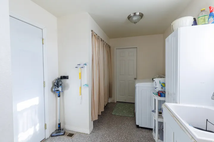 Utility area with durable flooring, a deep basin sink, and a flush-mount ceiling light fixture