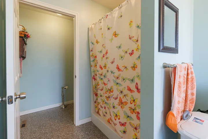 Bathroom featuring a shower-tub combination, light-toned walls, and a frameless mirror