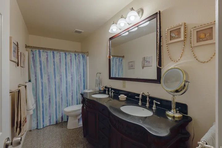 Double vanity with dark countertop, dual undermount sinks, and decorative wood-finish cabinetry
