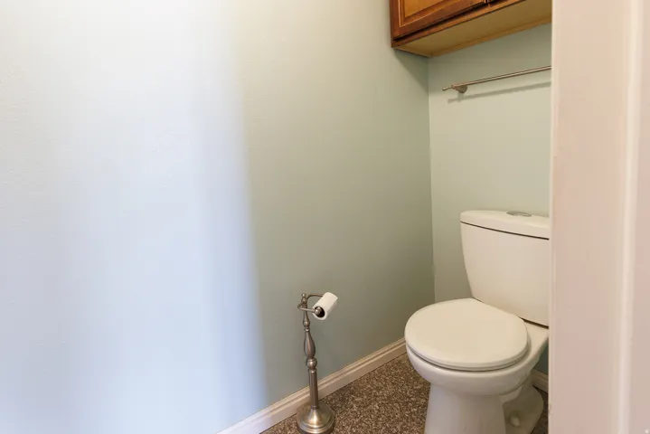 Wood-finish cabinetry with a chrome towel bar and white toilet