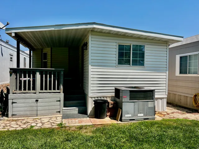 White horizontal siding exterior with a covered porch and railing, featuring exterior steps and a window with blinds