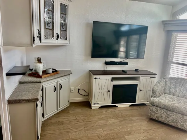 Wood-finish flooring, built-in cabinetry with decorative glass inserts, and a media console with an integrated electric fireplace
