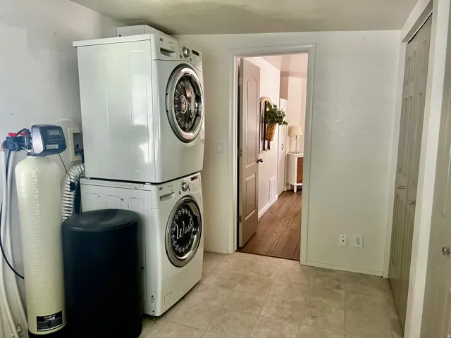 Laundry area with stacked washer and dryer appliances, featuring a water filtration system
