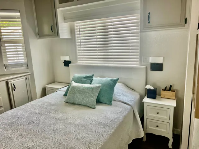 Built-in overhead cabinetry, integrated wall sconces, window with horizontal blinds, and a built-in storage cabinet