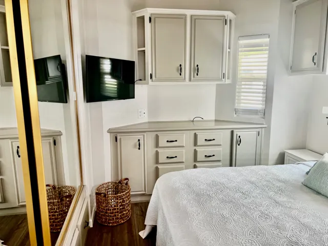 Built-in cabinetry with modern hardware, integrated media console, window with blinds, and wood-finish flooring