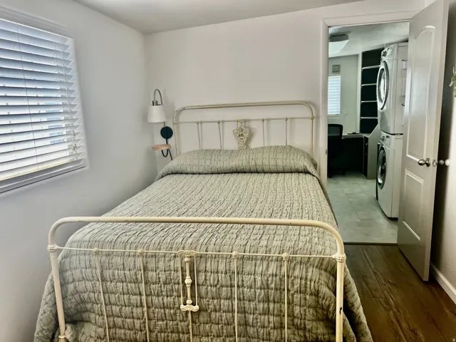 Wood-finish flooring throughout, white interior walls, and window with horizontal blinds