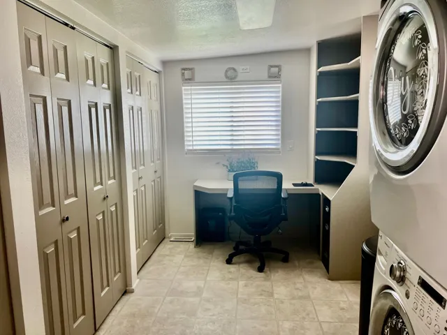 Office area featuring a built-in desk, shelving, window with blinds, and tile flooring