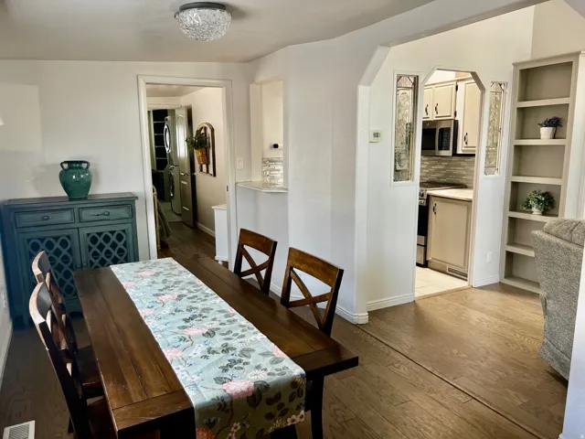 Wood-finish flooring throughout, built-in shelving, and an arched doorway with decorative glass panels