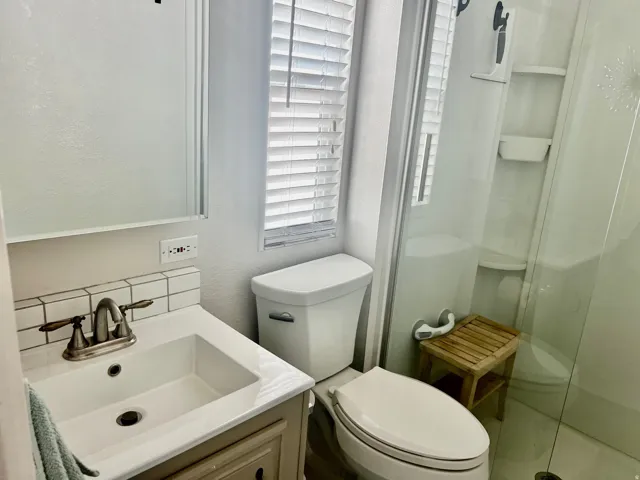 Vanity with white subway tile backsplash, brushed nickel faucet, and integrated sink