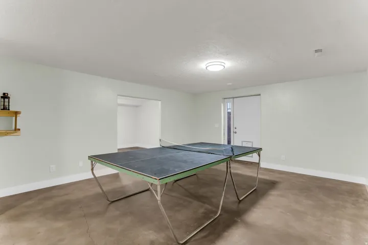 Spacious room with light-colored walls, durable concrete flooring, and an overhead flush-mount light fixture