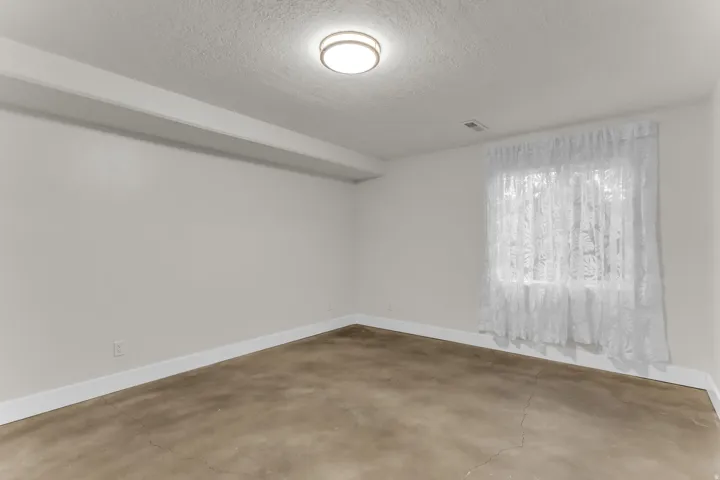 Recessed window, polished concrete flooring, surface-mount ceiling light fixture, white wall finishes, and exposed beam