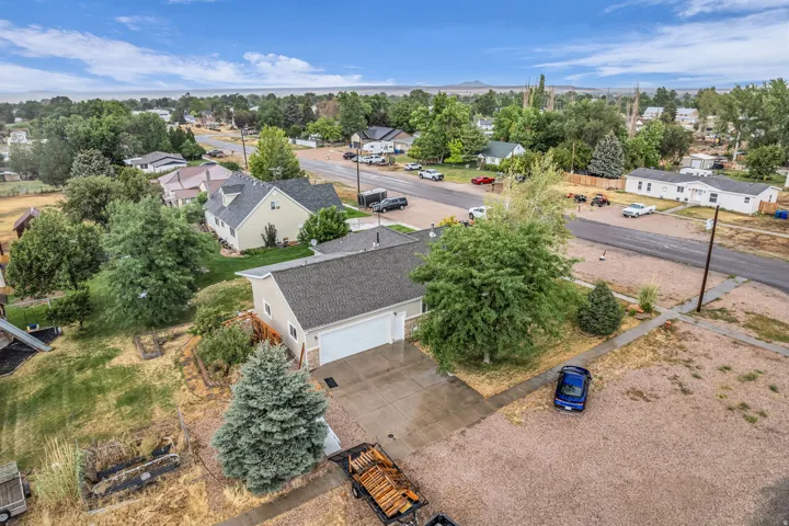 Two-car attached garage, paved driveway, established trees, and gravel landscaping