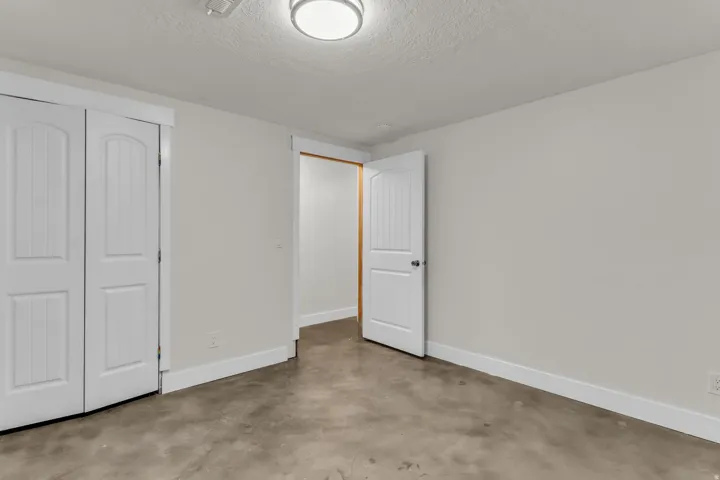 Concrete flooring with white trim, white walls, and a semi-flush ceiling light