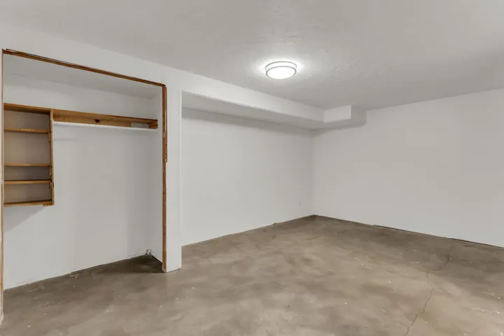 Expansive room with concrete flooring, recessed lighting, and a built-in closet with shelving and a hanging rod