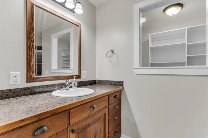 Elegant bathroom vanity featuring warm wood cabinetry with multiple drawers and hardware accents, paired with a speckled stone countertop and round undermount sink