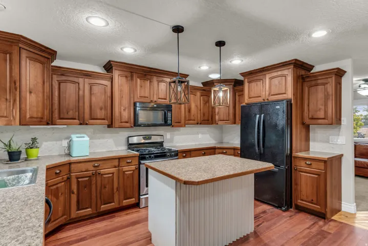Wood-finish flooring with a central island, recessed lighting, and wooden cabinetry