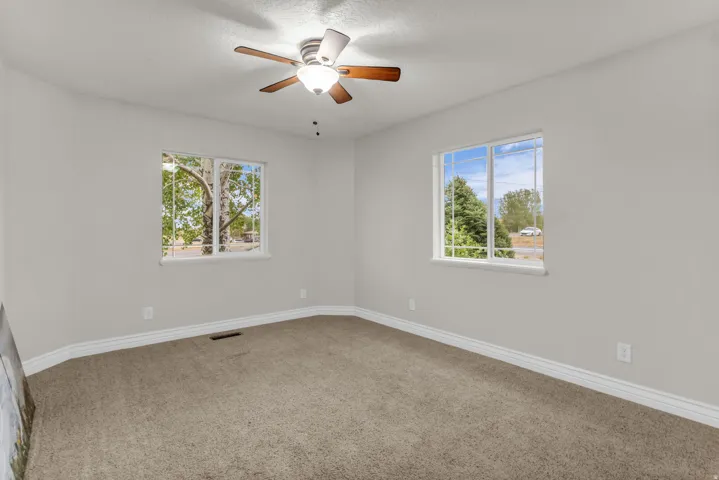 Carpeted flooring, white trim, dual windows, and ceiling fan with integrated lighting