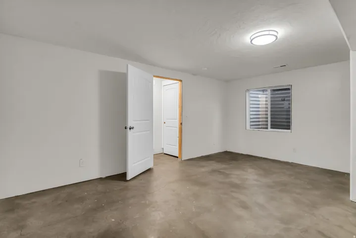 White walls, concrete flooring, white paneled doors, and a flush mount ceiling light