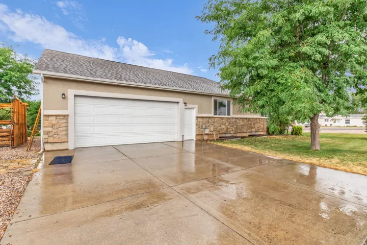 Two-car garage with a sectional door, stone veneer detailing, and a concrete driveway