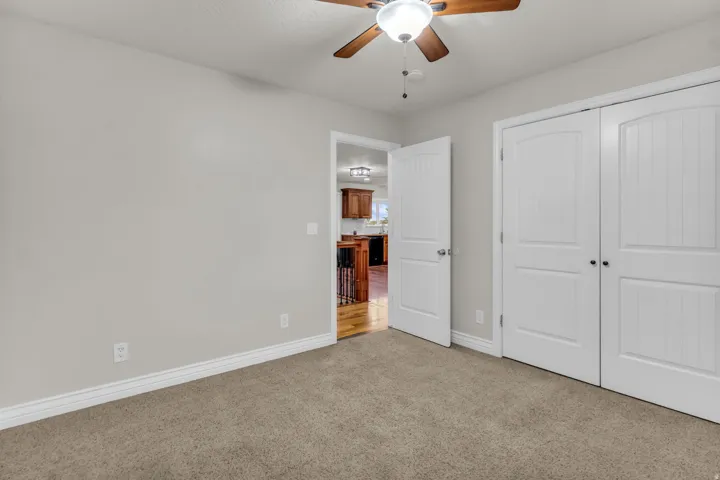 Neutral wall paint, carpet flooring, a ceiling fan with light, and white paneled doors