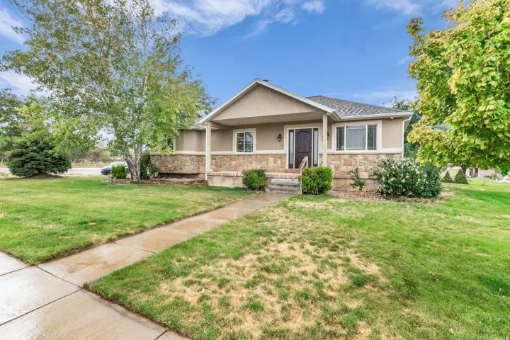 Single-story residence featuring a covered front porch, stone facade, and a dark entry door