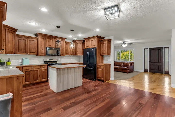 Wood-finish flooring, recessed lighting, wood cabinetry, built-in appliances, and a central kitchen island