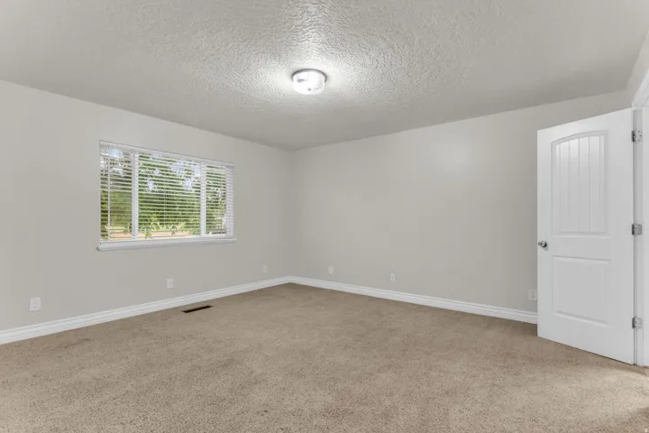 Neutral tone walls, carpeted flooring, white trim, recessed window, and a white paneled door