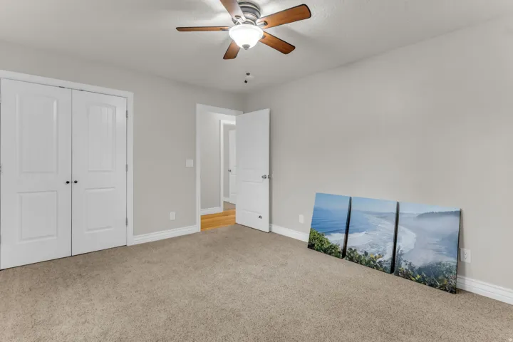 Carpeted room featuring a ceiling fan with integrated lighting, white interior doors, and light gray wall paint