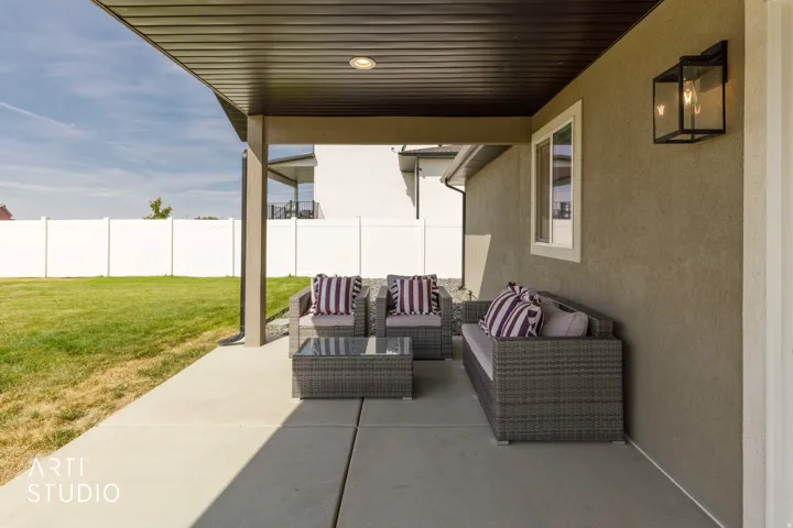 Covered concrete patio with recessed lighting, an exterior sconce, and a white privacy fence