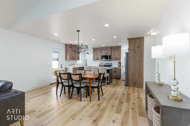 Open-concept living area featuring light wood-finish flooring, recessed lighting, and a modern chandelier