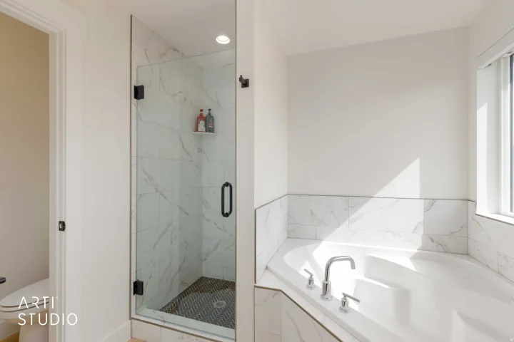 Glass-enclosed shower with black hardware, integrated shelving, and a patterned tile floor