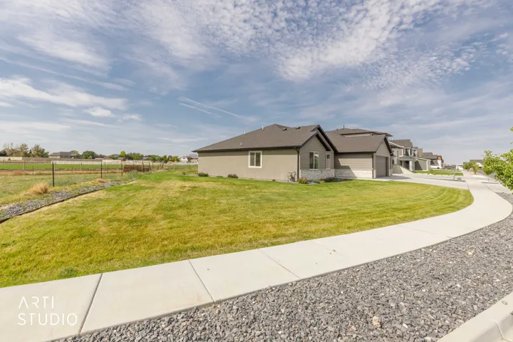 Contemporary stucco exterior, stone accents, attached garage, concrete walkway, and manicured lawn