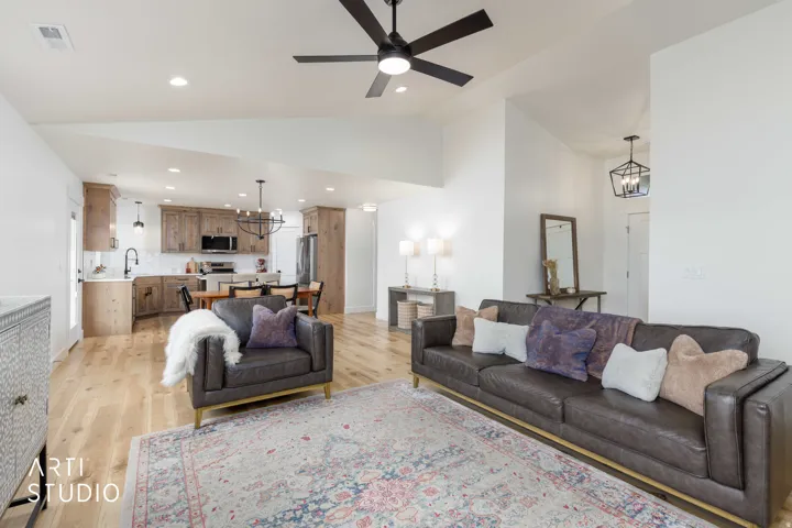 Vaulted ceilings with recessed lighting, wood-finish flooring, open-concept layout, modern ceiling fan, and built-in kitchen cabinetry