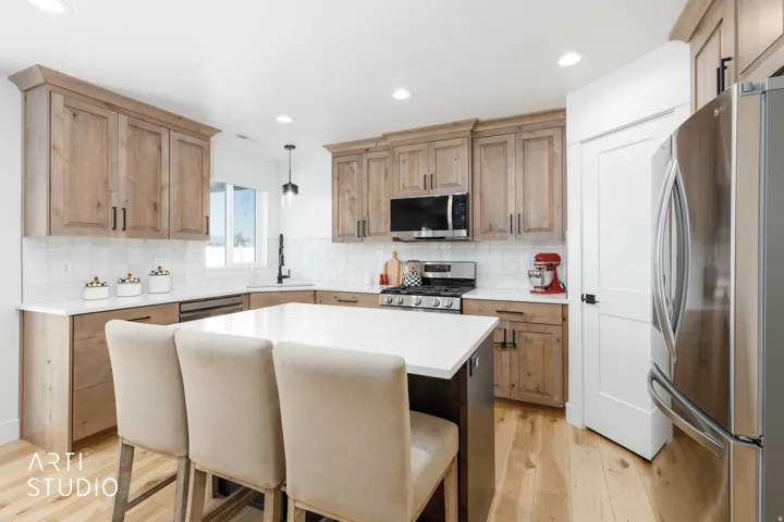 Kitchen featuring natural wood cabinetry, white countertops, stainless steel appliances, a center island, and wood-finish flooring