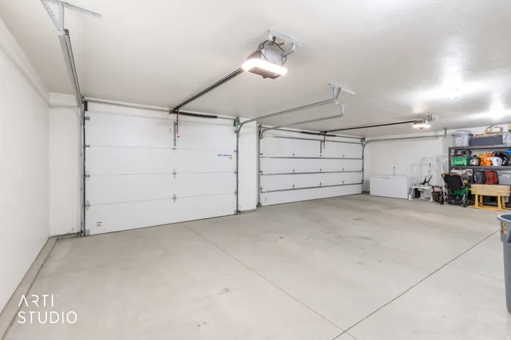 Two-car garage featuring concrete flooring, white sectional garage doors, and overhead lighting