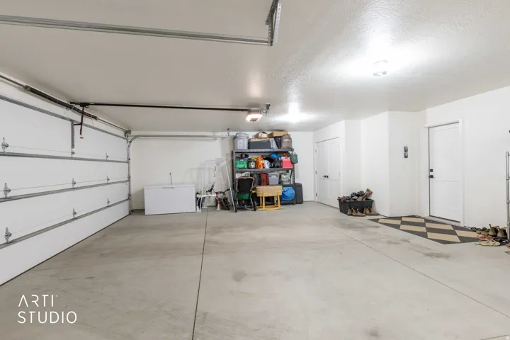 Spacious garage featuring a concrete floor, overhead lighting, and white panel garage doors