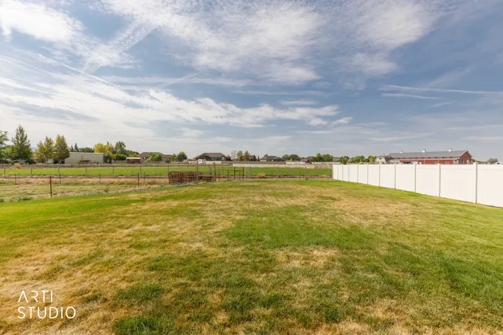 Expansive grassy area with a white privacy fence
