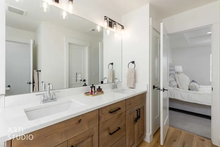 Dual vanity with undermount sinks, wood-finish cabinetry, and quartz countertops