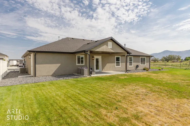 Stucco exterior with a covered patio, multiple windows, and a fenced perimeter