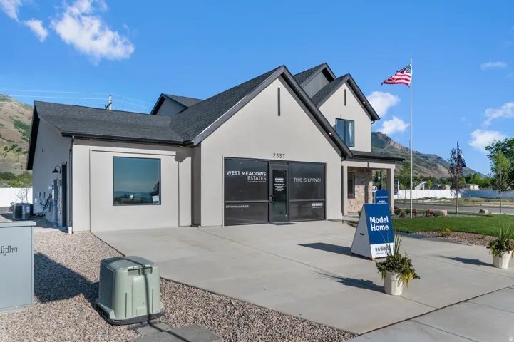 Contemporary exterior with a dark shingle roof, light stucco siding, stone accents, and a covered entry